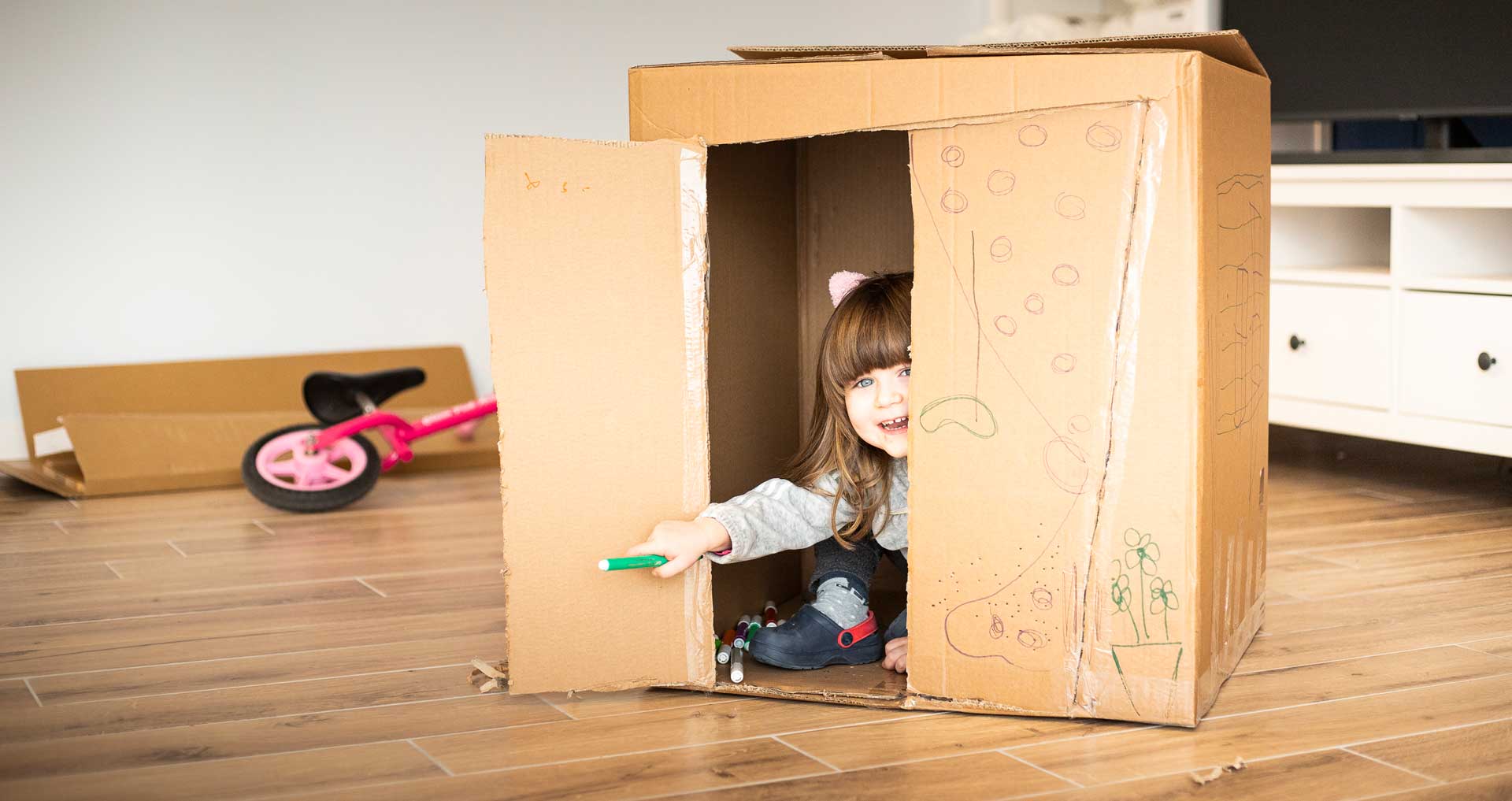 A little girl is playing in a cardboard box