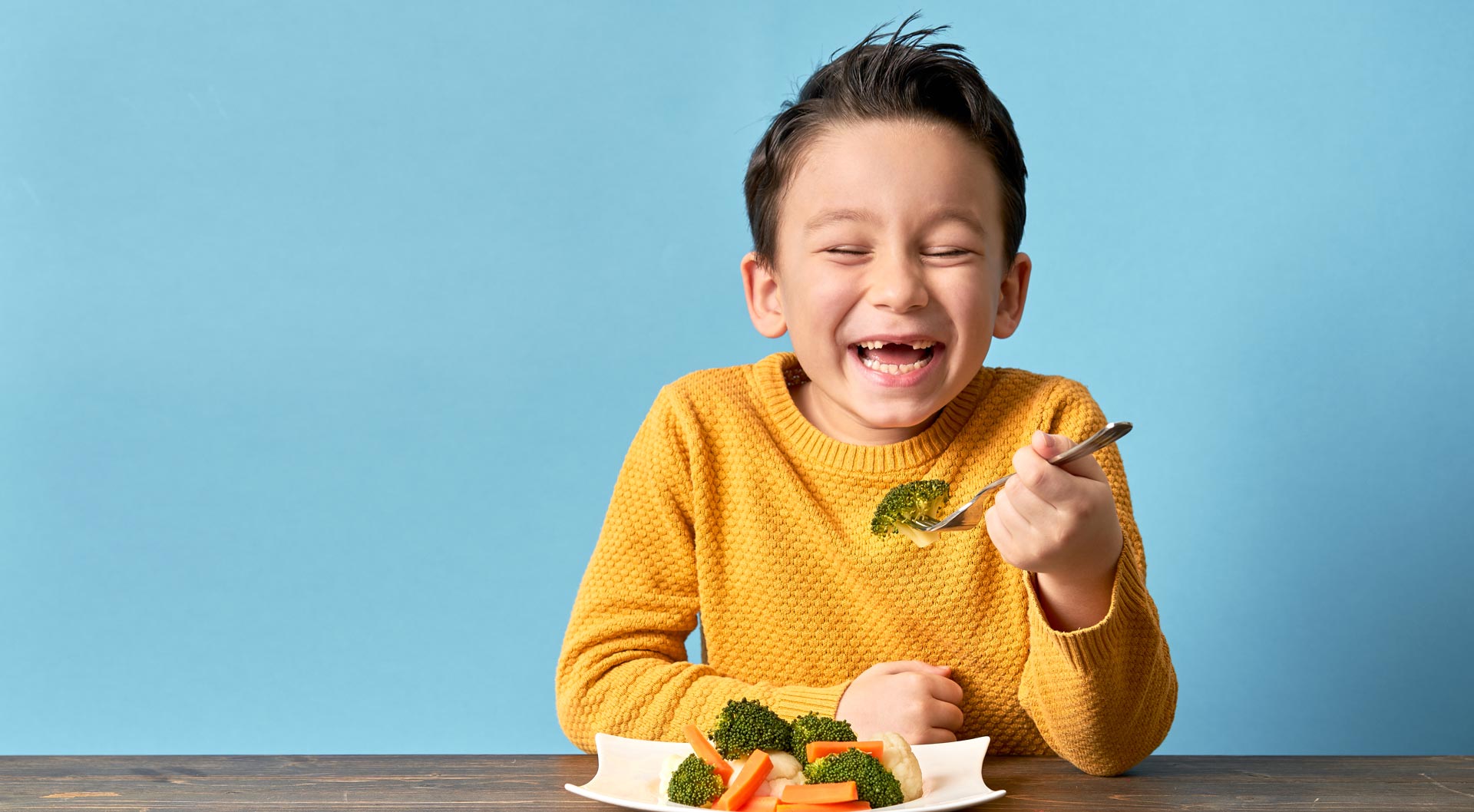 A child happily eats his broccoli. 