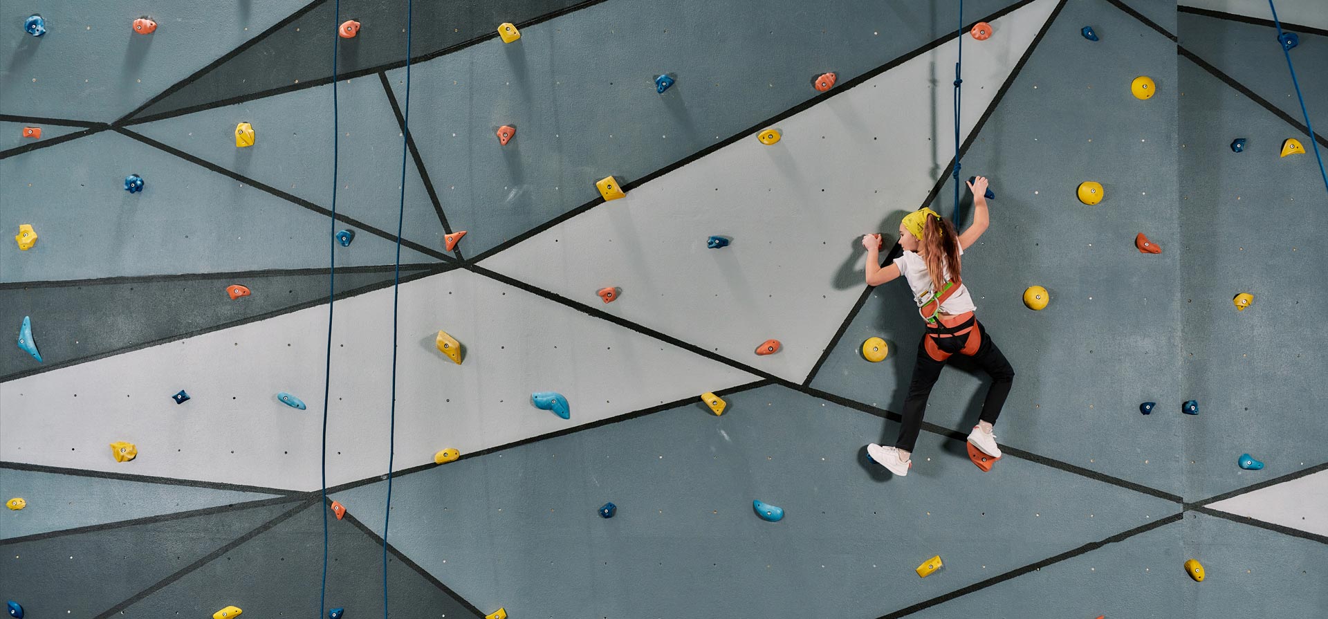 A young girl climbing on an indoor climbing wall.