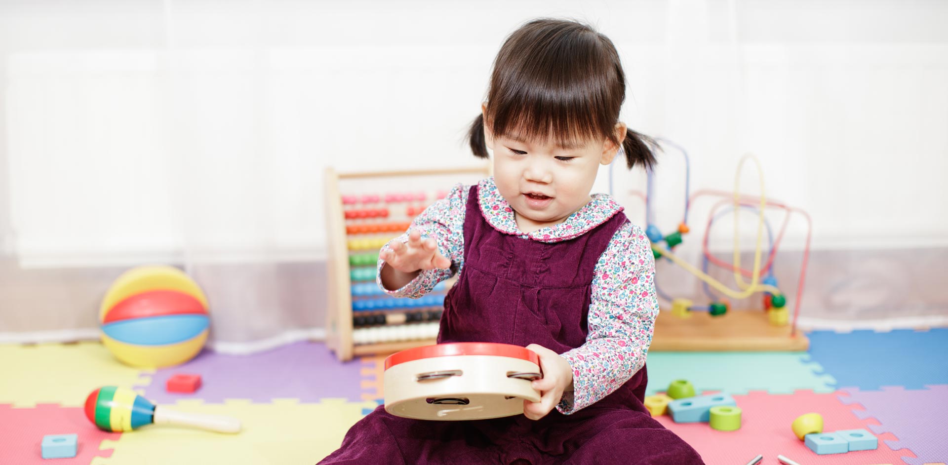 A toddler plays with a tambourine