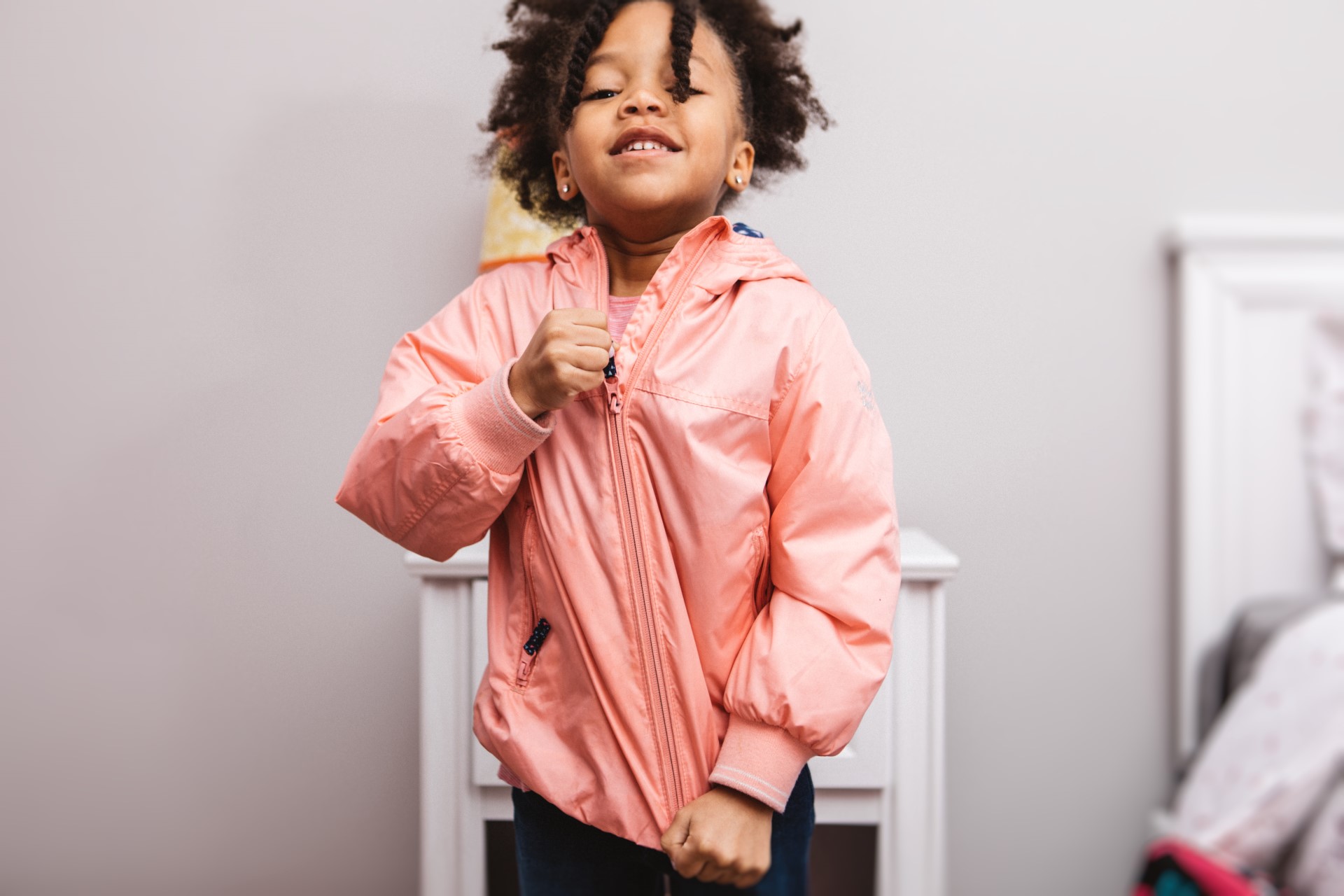 A child putting her coat on and zipping it up