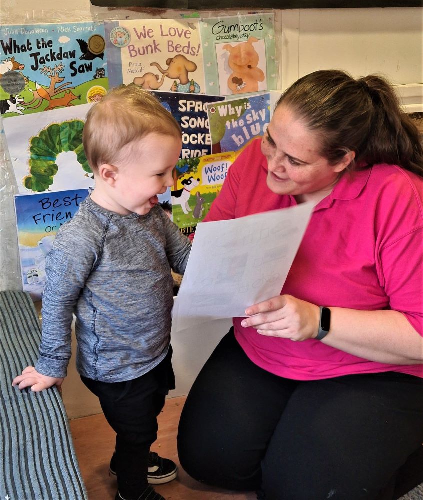 A nursery worker is helping a toddler with his vocabulary