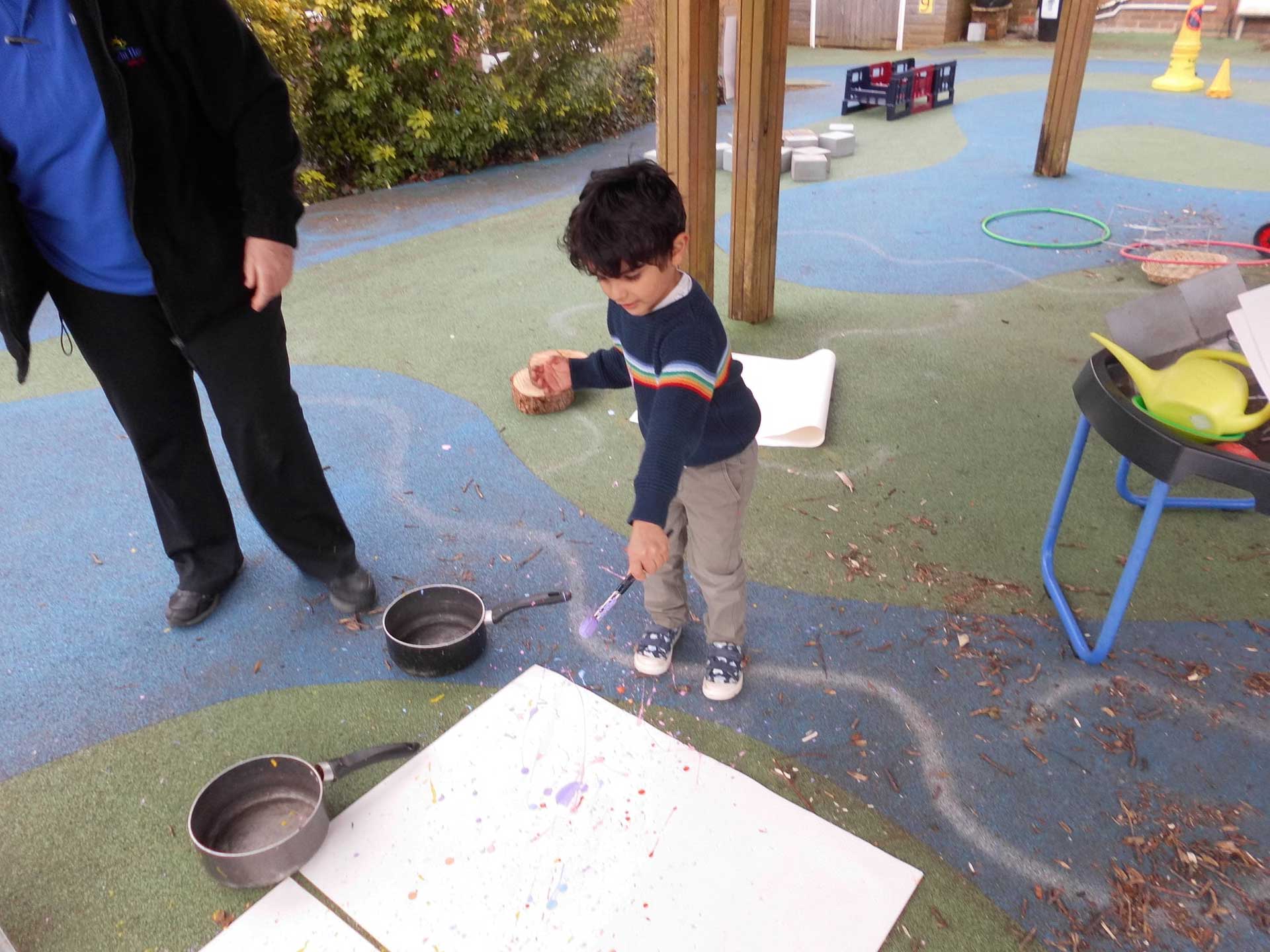 A child splatters paint on to a large piece of paper