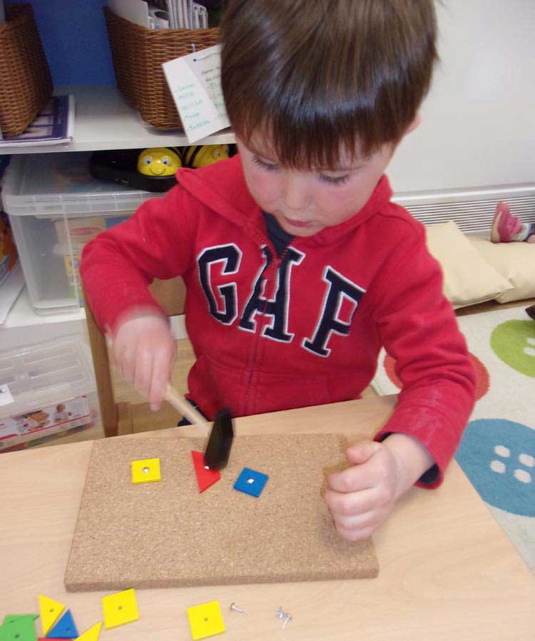 A child uses a small hammer to practice his fine motor skills