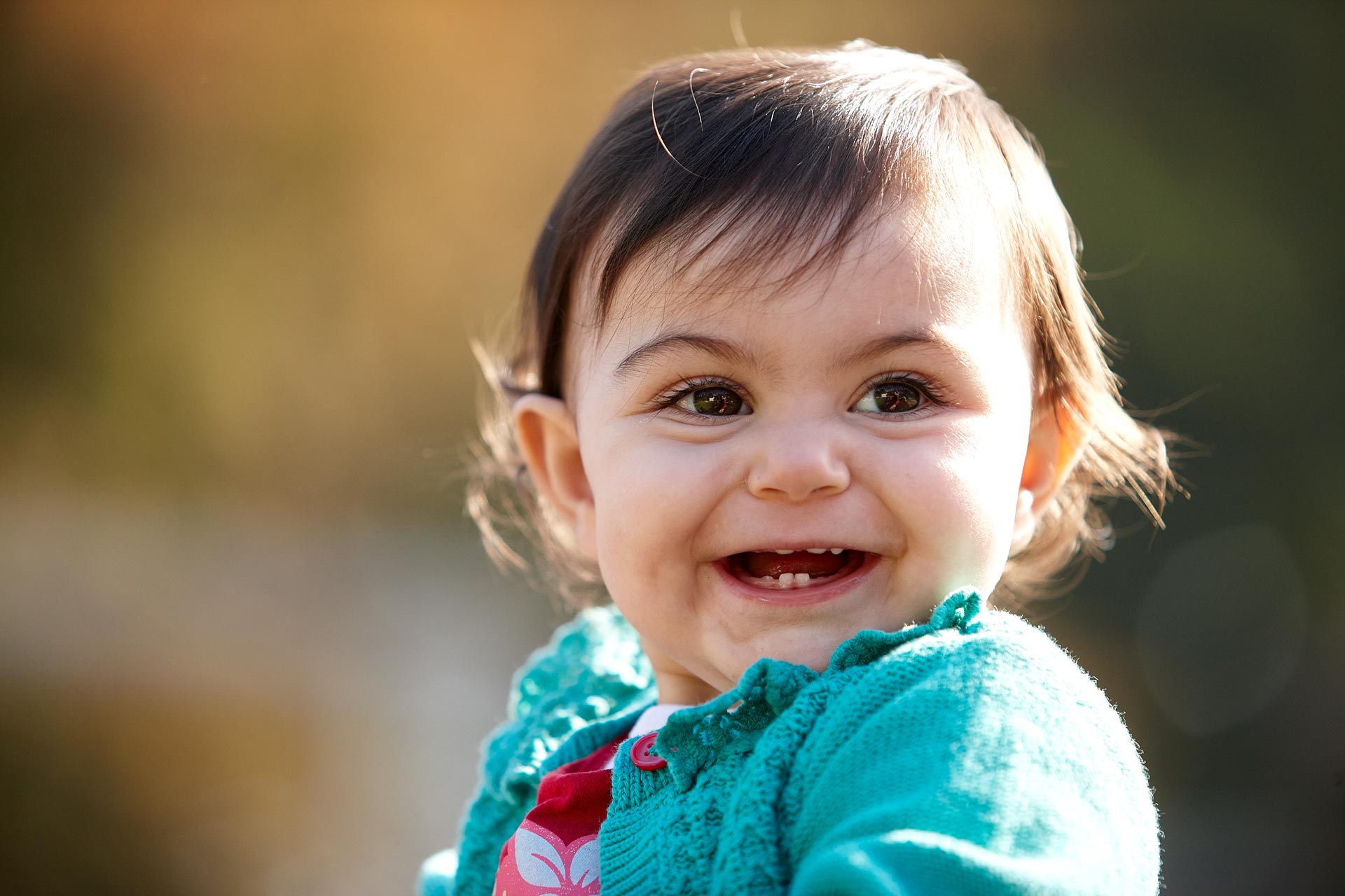 A baby smiling open mouthed, showing emerging teeth