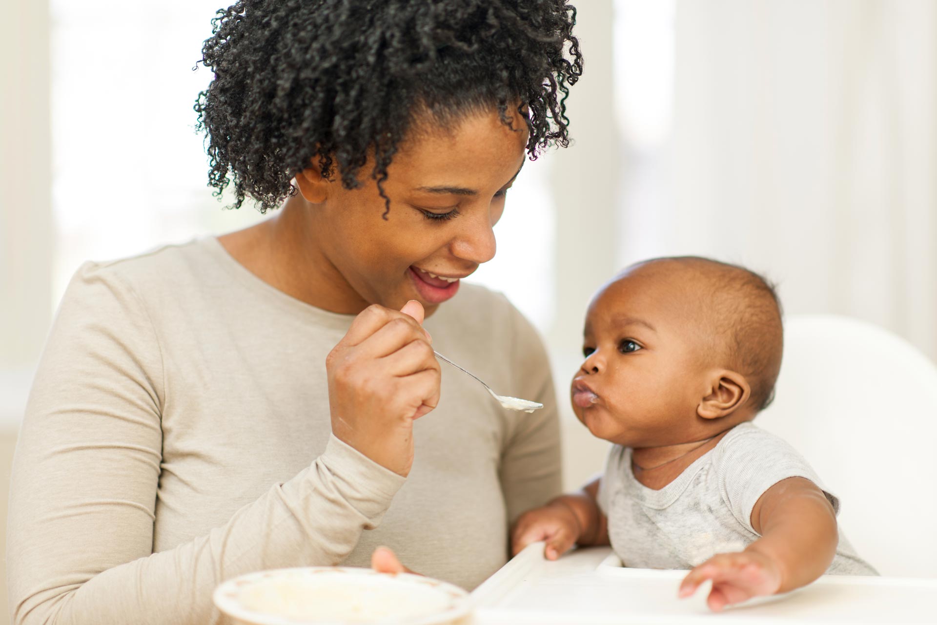 A mother feeds her baby with a weaning spoon
