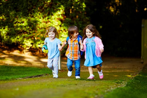 Three children holding hands, walking and talking