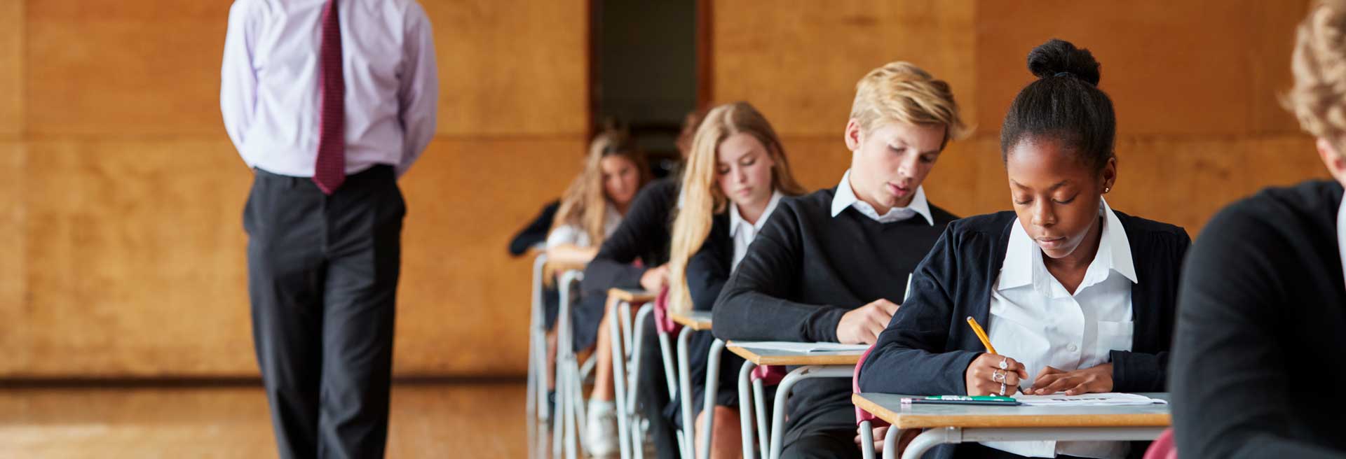 A row of secondary school pupils are taking an exam