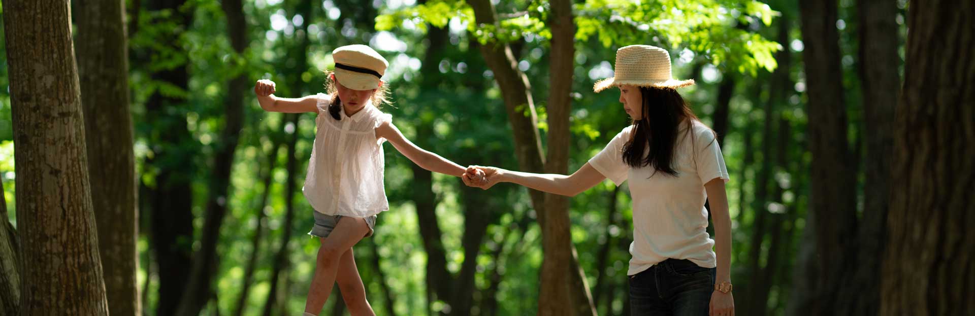 A mother helps her child navigate balance poles in the woods