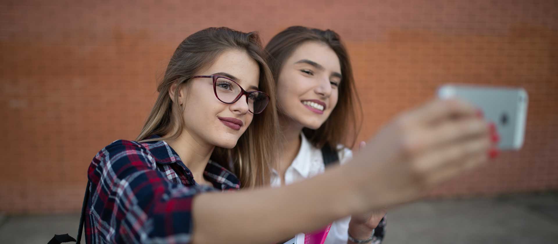 A teenage girl is taking a selfie with her friend