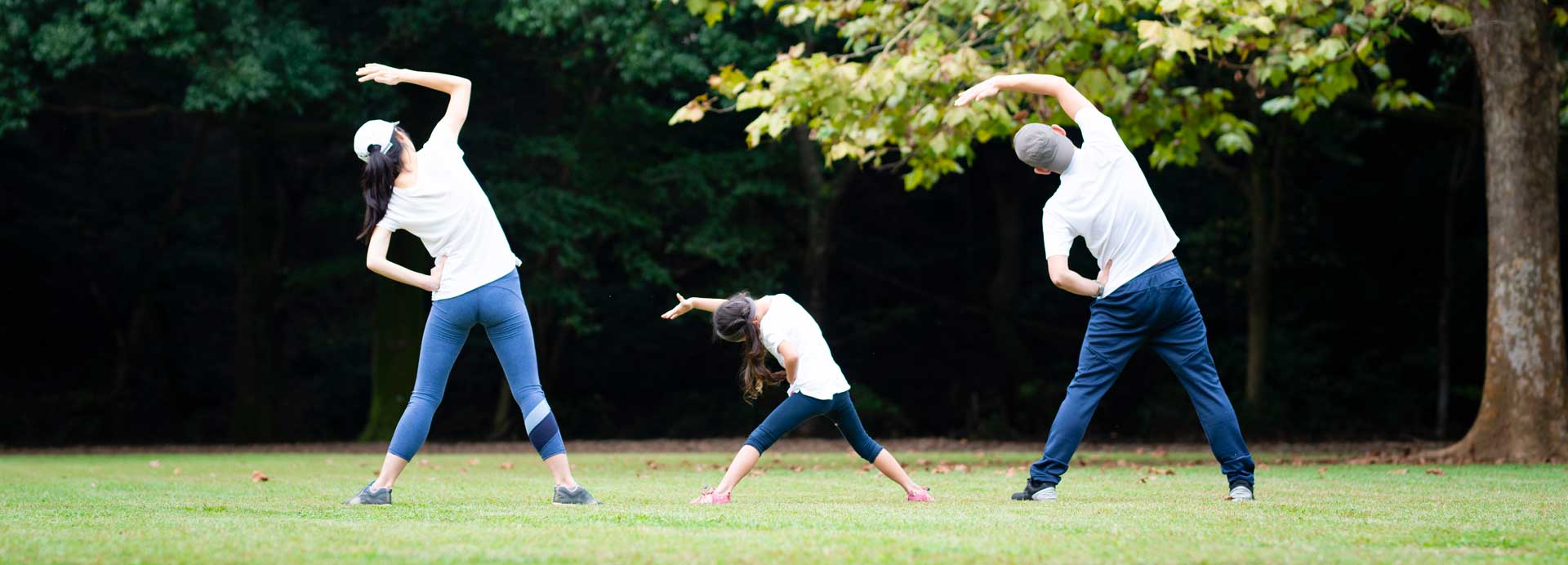 A family of three are exercising in a park